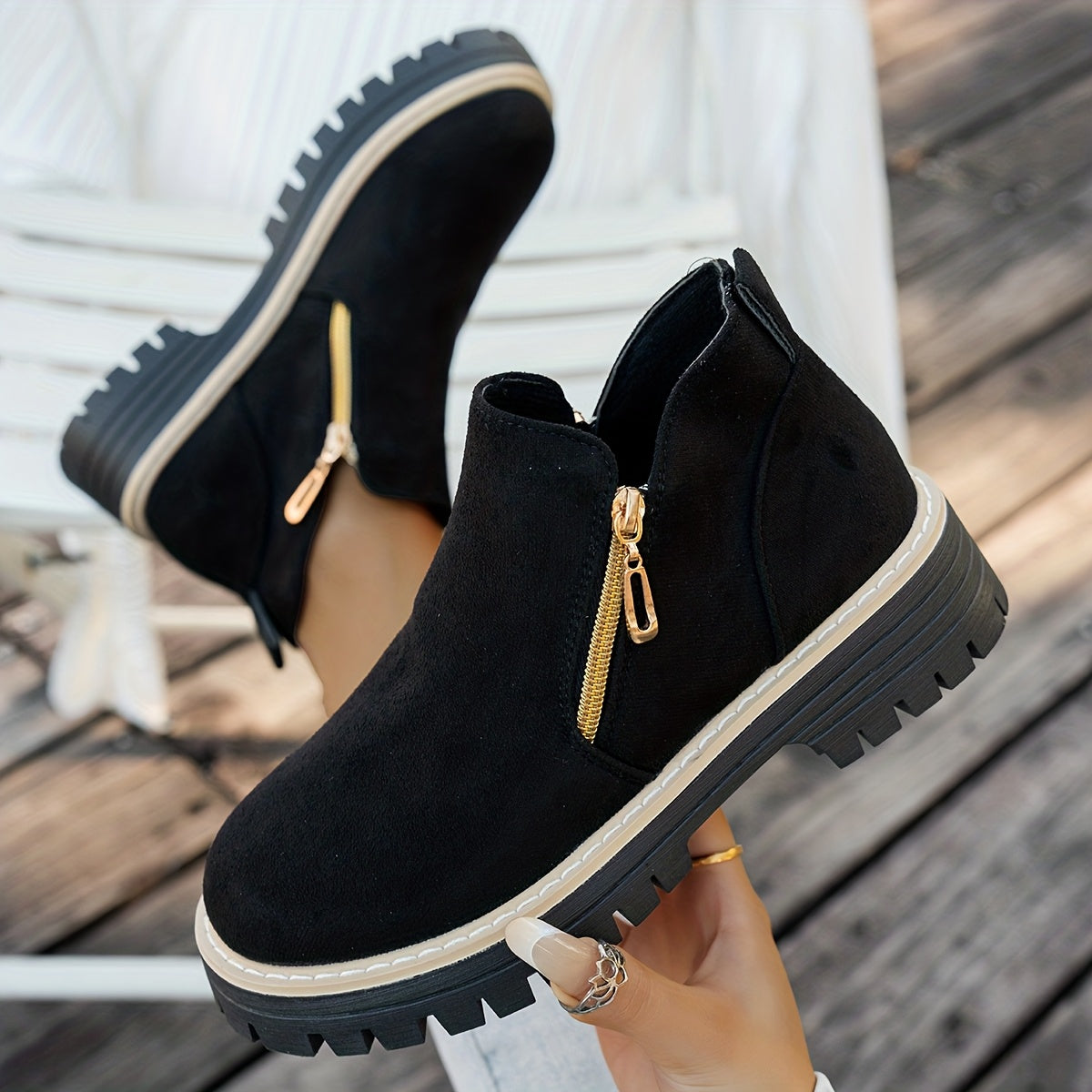 Black ELARA ankle boots held to show side zips and chunky soles